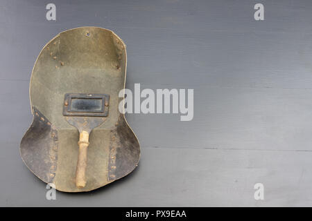 Welder's mask and gloves on a black workshop table. Protective clothing for workers in metalware. Dark background. Stock Photo