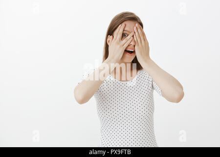 https://l450v.alamy.com/450v/px9ftb/woman-cannot-wait-wanting-see-what-waits-her-closing-eyes-with-palms-peeking-with-one-eye-through-fingers-smiling-gasping-and-gazing-with-amused-and-amazed-expression-standing-over-gray-wall-px9ftb.jpg