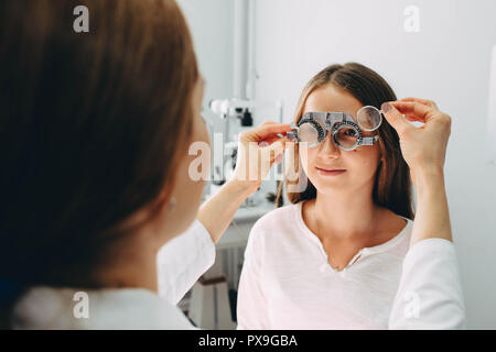 Eye doctor examining girls vision using a trial frame Stock Photo