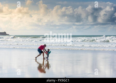 A grandfather having fun with his granddaughter on Fistral Beach in Newquay in Cornwall. Stock Photo