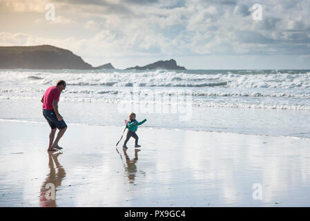 A grandfather having fun chasing his granddaughter on Fistral Beach in Newquay in Cornwall. Stock Photo