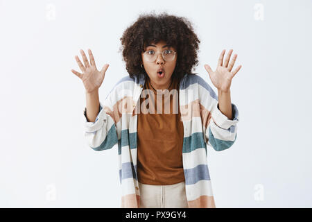 Stay were you are. Excited sociable and creative female with afro hairstyle raising palms and folding lips telling scary story while on trip with friends sitting by fire being persuasive and emotive Stock Photo