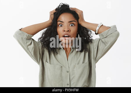 Waist-up shot of concerned girl in stupor. Portrait of shocked african american businesswoman standing anxious and shocked opening mouth holding hands on head desperate and devastated Stock Photo