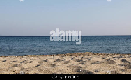 Summer view of quiet waves on the sea horizon line on a sunny day. Seen from the silver sandy beach. Stock Photo