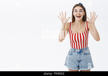 Girl received ten millions being surprised and amazed. Portrait of joyful amused and excited good-looking female raising palms near shoulders smiling broadly while telling excellent news Stock Photo