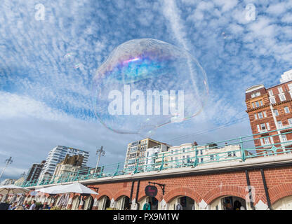 Large bubble floating in the sky in a city with blue sky & fluffy clouds in Brighton, UK. Freedom concept. Floating freely. Stock Photo
