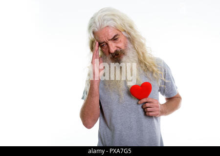 Studio shot of senior bearded man holding red heart while having Stock Photo