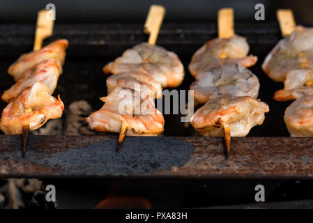 Grilled fried prawns on skewers on metal grid Stock Photo