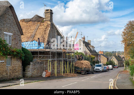 Master Thatcher removing old thatch from a cottage in the village of  Kings Sutton, Northamptonshire, England Stock Photo