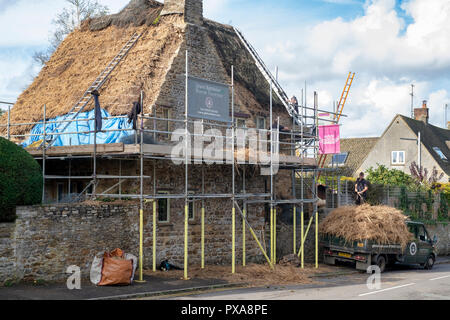 Master Thatcher removing old thatch from a cottage in the village of  Kings Sutton, Northamptonshire, England Stock Photo