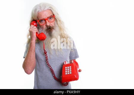 Studio shot of senior bearded man talking on old telephone Stock Photo