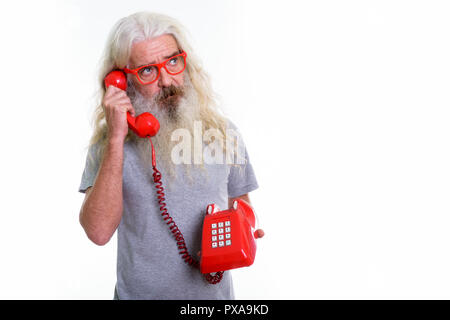 Studio shot of senior bearded man thinking while talking on old  Stock Photo