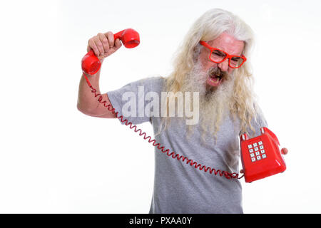 Studio shot of senior bearded man looking angry and shouting whi Stock Photo