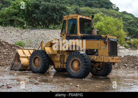 Yellow bulldozer takes a break on the river bank Stock Photo