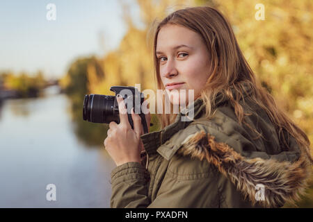 Young woman with slr camera in his hand is looking into camera Stock Photo