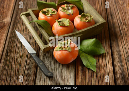 pile of ripe persimmons on wooden table - closeup Stock Photo