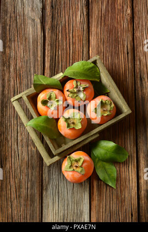 pile of ripe persimmons on wooden table - closeup Stock Photo