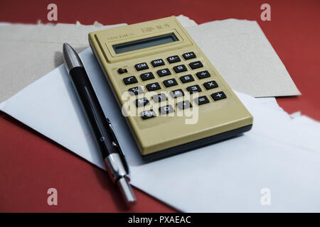 On the red table, a Toshiba HB-101 calculator from the seventies, still working. Next to it, a pen and opened envelopes. Stock Photo