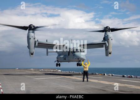 181015-N-WH681-0198 ATLANTIC OCEAN (Oct. 15, 2018) Aviation Boatswain Mate (Handling) 2nd Class Jamel Agee directs a MV-22 Osprey to depart the flight deck of the Wasp-class amphibious assault ship USS Kearsarge (LHD 3) the Carrier Strike Group (CSG) 4 composite training unit exercise (COMPTUEX). COMPTUEX is the final pre-deployment exercise that certifies the combined Kearsarge Amphibious Ready Group (ARG) and 22nd Marine Expeditionary Unit's (MEU) abilities to conduct military operations at sea and project power ashore through joint planning and execution of challenging and realistic trainin Stock Photo