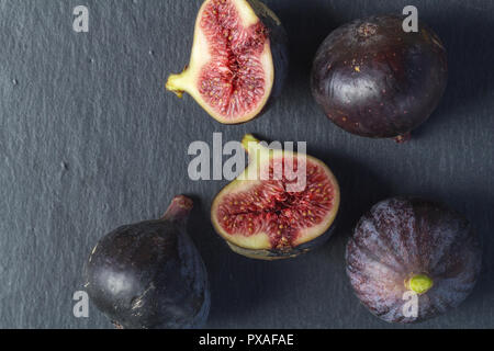 Figs isolated on black slate background - top view close up photo of whole and cut figs Stock Photo
