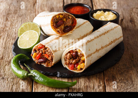 Traditional grilled burritos with beef and vegetables served with sauces close-up on the table. horizontal Stock Photo