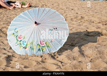 An Umbrella sits in the sand on a beach Stock Photo