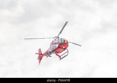 Red rescue helicopter fly in snowy mountains Stock Photo