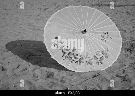 An Umbrella sits in the sand on a beach Stock Photo