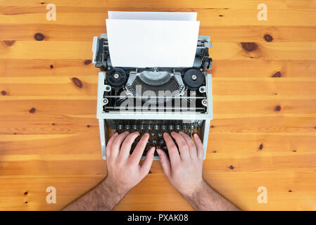 Writer's hands. Old retro typewriter on wooden desk. Stock Photo