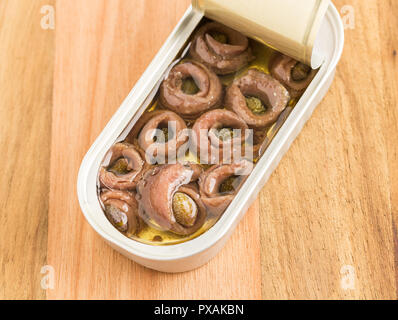 Rolled anchovies in tin on wooden background Stock Photo