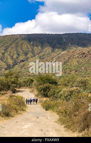 A group of hikers walking along the dusty trail towards Mount Longonot in the distance, Kenya Stock Photo