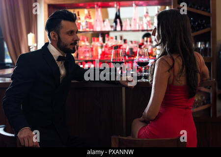 Handsome couple of lovers flirting in the pub and drinking red wine. Stock Photo