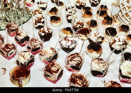 Many cups with different types of desserts based on mousse and panna cotta garnished with chocolate and cream Stock Photo