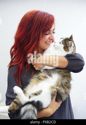 Beautiful young red haired woman cuddling with her cute,big and fluffy pet cat Stock Photo