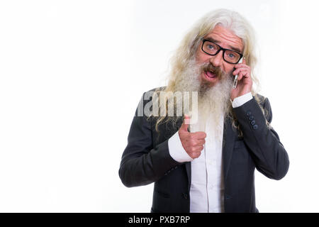 Studio shot of senior bearded businessman talking on mobile phon Stock Photo
