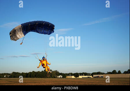 Skydiver under a dark blue little canopy of a parachute is landing on airfield, close-up. High-speed landing of a parachuter against the background of Stock Photo