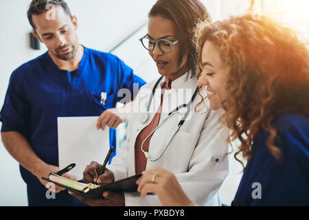 Diverse group of young doctors standing in a hospital corridor discussing a patient's dignosis Stock Photo