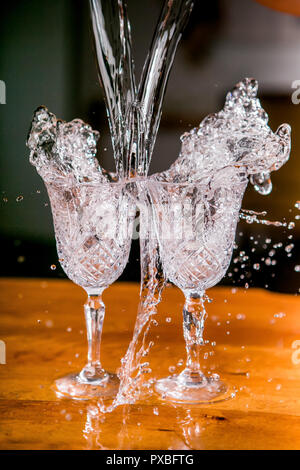 Frozen splashes in two beautiful wine glasses on a table against a dark background. close-up Stock Photo
