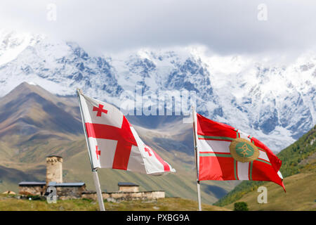 Flying flag of Georgia and flag of Georgian Border Police. With Svan's tower and mountains on the background, Svaneti. Stock Photo