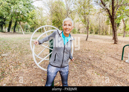 Elderly Woman In Sports Clothes Exercising At Outdoor Fitness Park, Healthy Lifestyle Mature People. Stock Photo