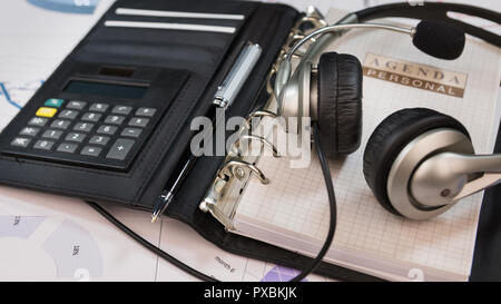 Close-up, headset lying on an organizer notepad. Call center table. Stock Photo