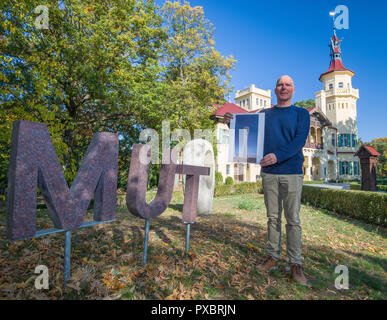 Storkow, Germany. 11th Oct, 2018. Rainer Opolka, entrepreneur and artist of the company Zweibrüder Kunst- und Kultur GmbH, stands next to the stroke 'MUT' in front of his castle Hubertushöhe and shows a design of an observation tower. Rainer Opolka wants to develop the area around Hubertushöhe Castle into an art and literature park. (to dpa-KORR 'From elitist castle hotel to art and literature park for all' from 21.10.2018) Credit: Patrick Pleul/ZB/dpa/Alamy Live News Stock Photo