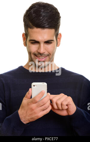 Face of young happy Persian man smiling and using mobile phone t Stock Photo
