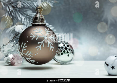 decorative glass balls and jingle bells for christmas tree on grey background with blurred fir tree branch Stock Photo