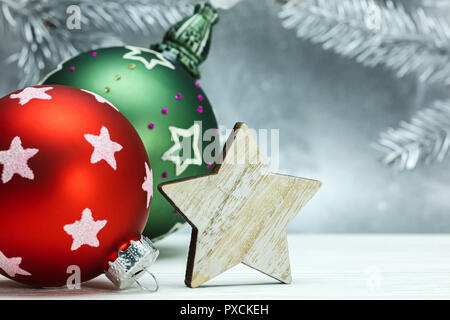 red and green christmas balls and wooden decorative star on blurred silver background with fir tree branches Stock Photo