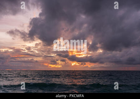 Dramatic storm clouds gather over the Andaman sea, Thailand, during sunset.  As seen from the shoreline. Stock Photo