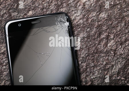 Smartphone with broken glass on display and copy space on a stone surface Stock Photo