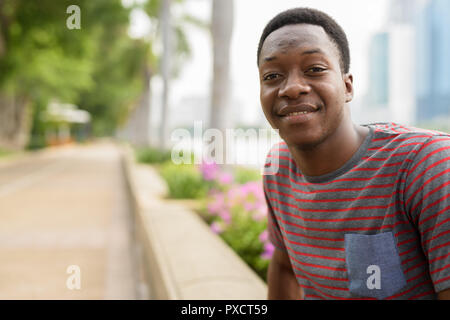 Young happy African man relaxing at the park and smiling Stock Photo