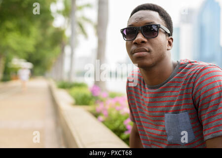 Young handsome African man wearing sunglasses and relaxing at the park Stock Photo