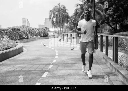 Black and white image of young African man running outdoors in park Stock Photo